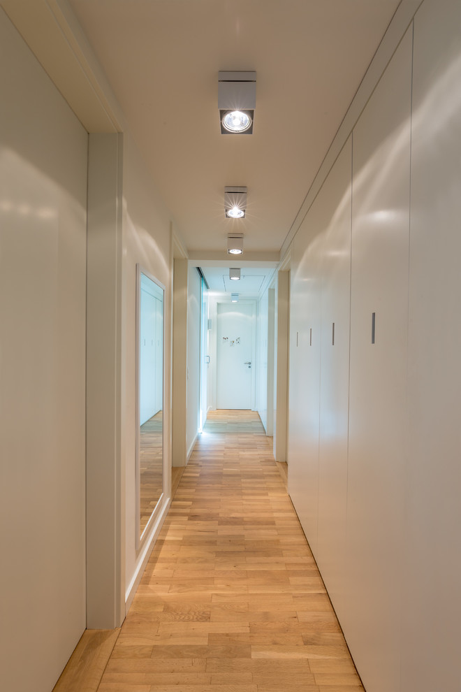 Foto di un ingresso o corridoio minimal di medie dimensioni con pareti bianche e pavimento in legno massello medio