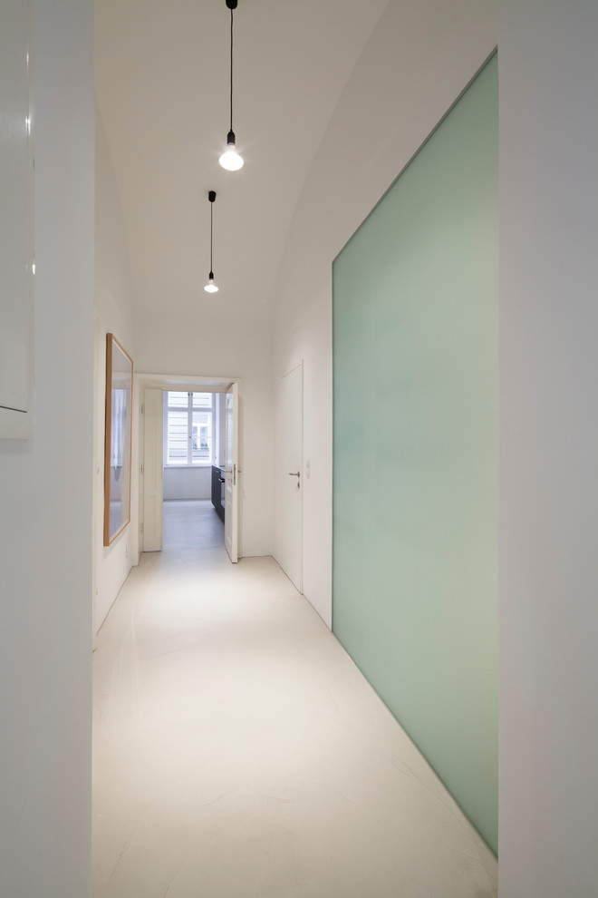Idee per un ingresso o corridoio minimalista di medie dimensioni con pareti bianche, pavimento in cemento e pavimento beige