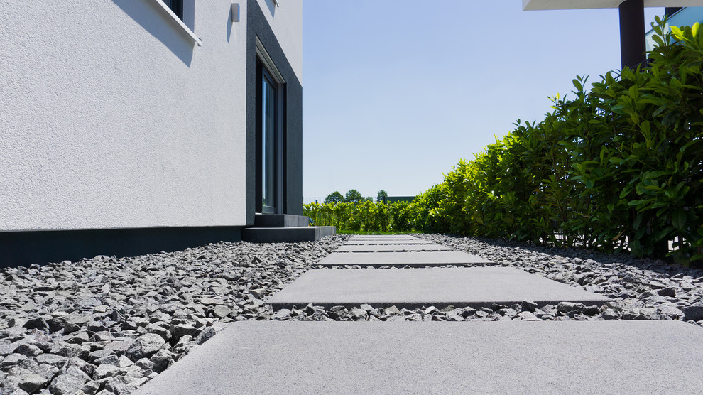 Foto di un giardino minimalista esposto in pieno sole dietro casa in estate con un ingresso o sentiero e pavimentazioni in cemento
