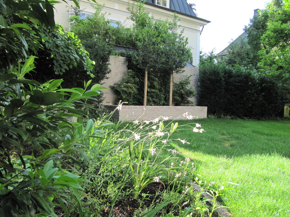 Inspiration för en vintage trädgård på våren, med en stödmur och marksten i tegel