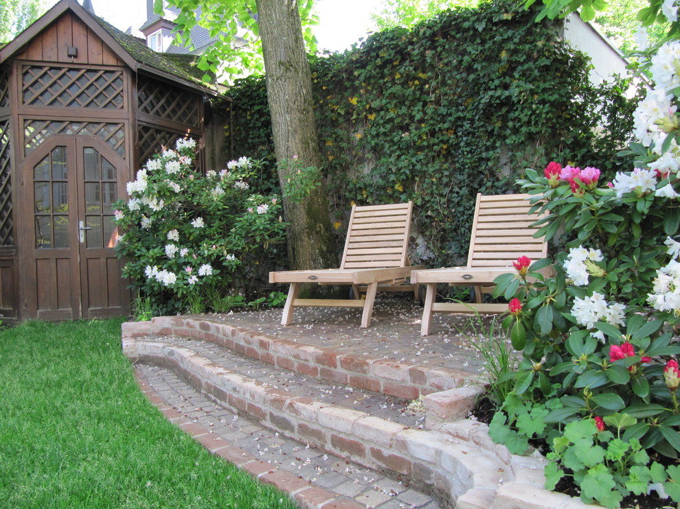 Idéer för en klassisk trädgård på våren, med en stödmur och marksten i tegel