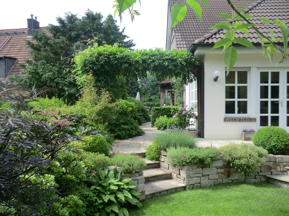 Photo of a medium sized rural side formal full sun garden for summer in Essen with a garden path and natural stone paving.