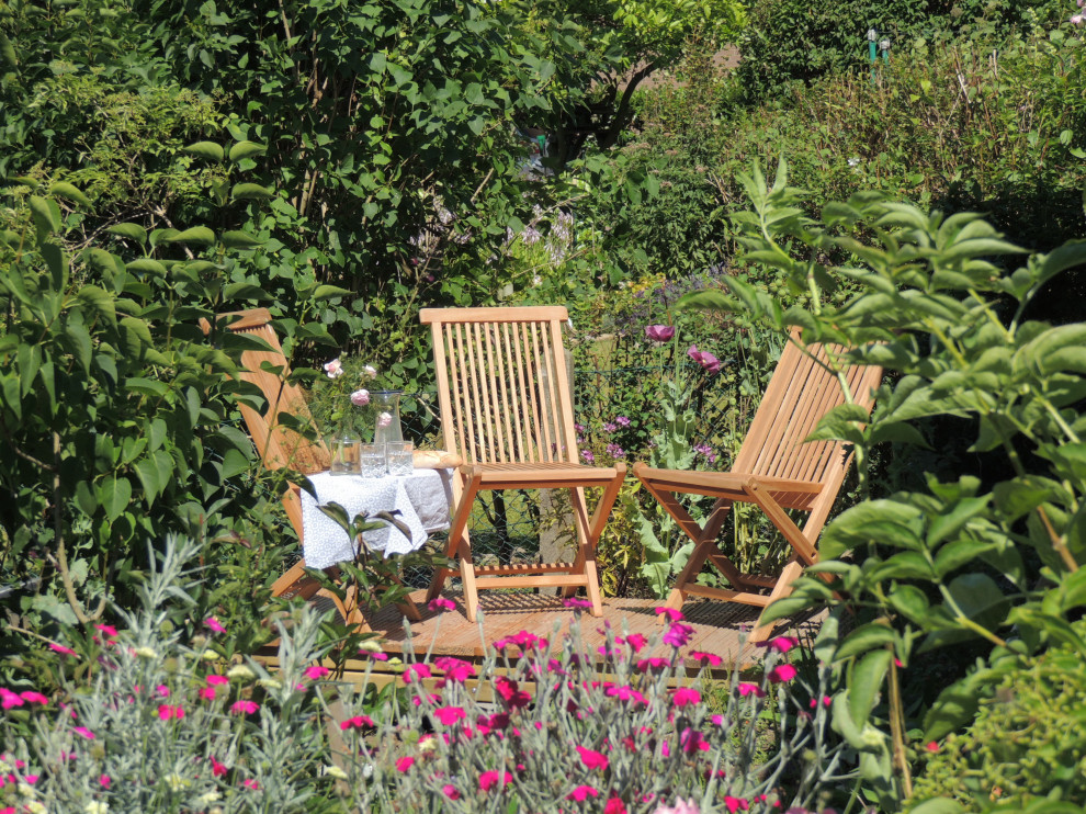 Exempel på en mellanstor lantlig trädgård i full sol blomsterrabatt och längs med huset på sommaren, med trädäck