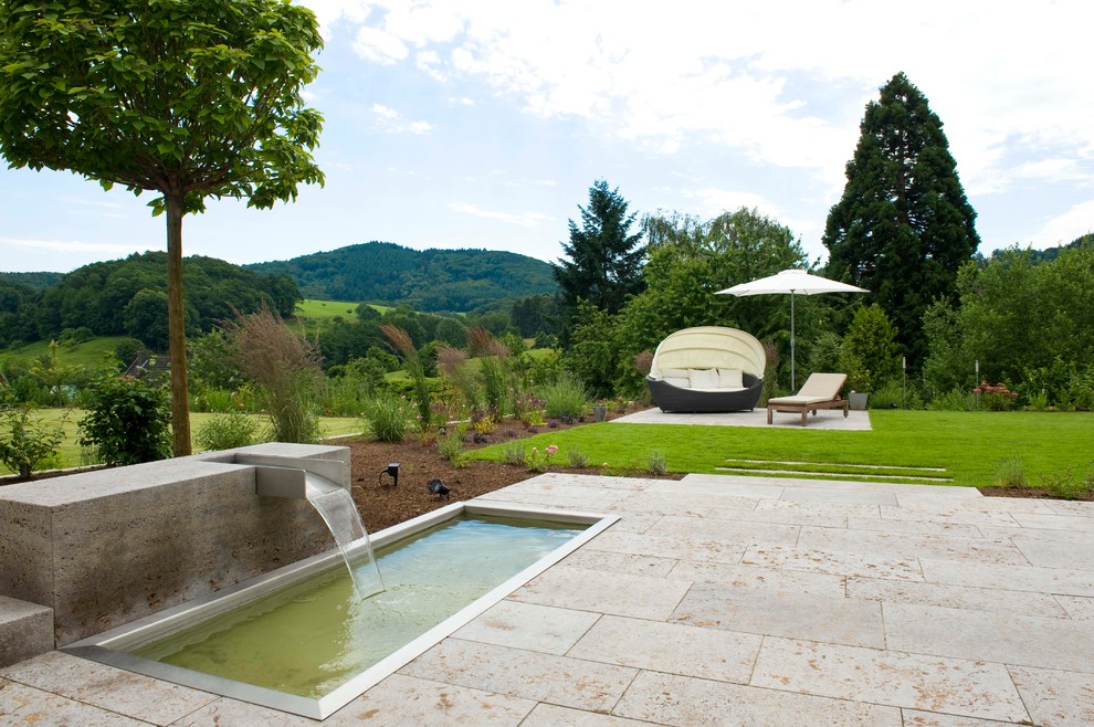 Inspiration för stora moderna trädgårdar i full sol, med en fontän och naturstensplattor