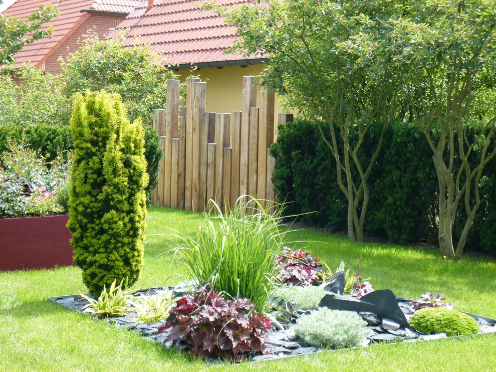 This is an example of a medium sized contemporary side partial sun garden for spring in Other with a flowerbed and natural stone paving.