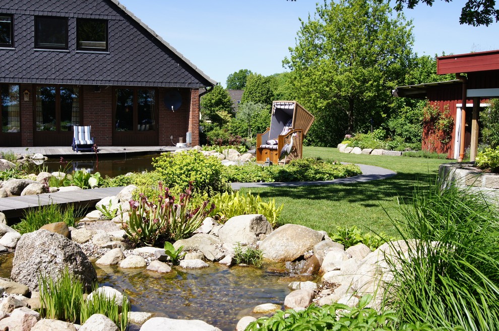 Modelo de camino de jardín de estilo de casa de campo grande en patio trasero con exposición parcial al sol y entablado