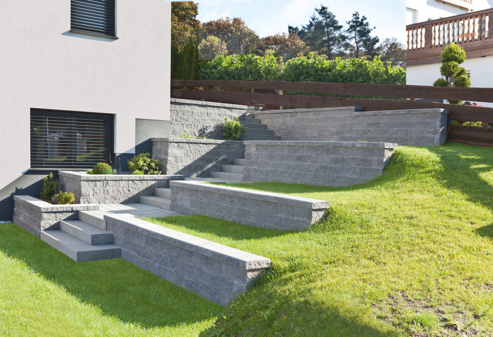 Источник вдохновения для домашнего уюта: участок и сад на склоне в современном стиле с подпорной стенкой и мощением тротуарной плиткой