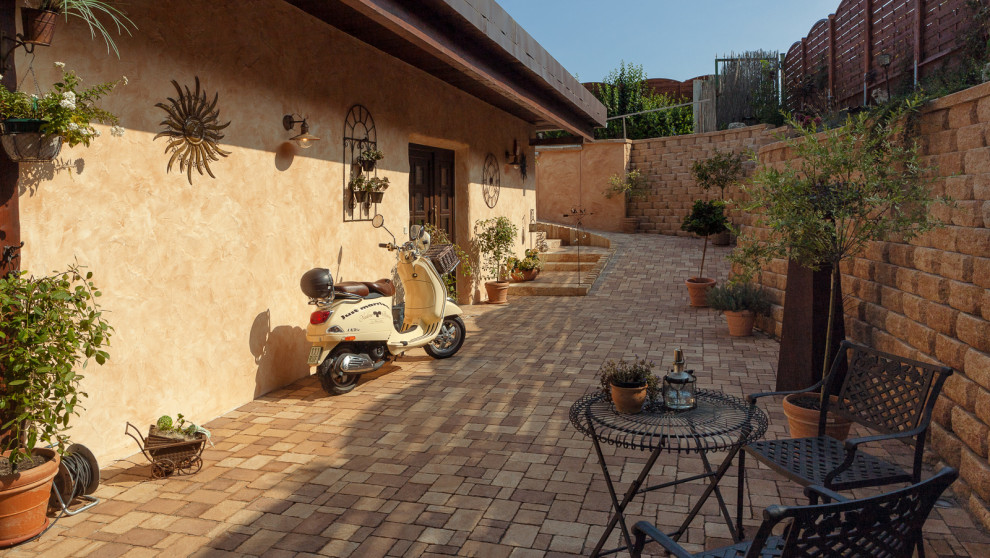 Photo of a mediterranean sloped garden with a retaining wall and concrete paving.