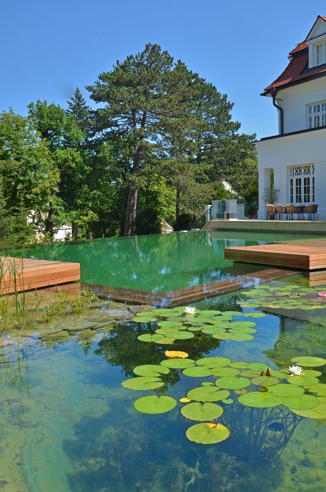 Modelo de jardín tradicional grande en verano en patio lateral con jardín francés, estanque, exposición total al sol y entablado