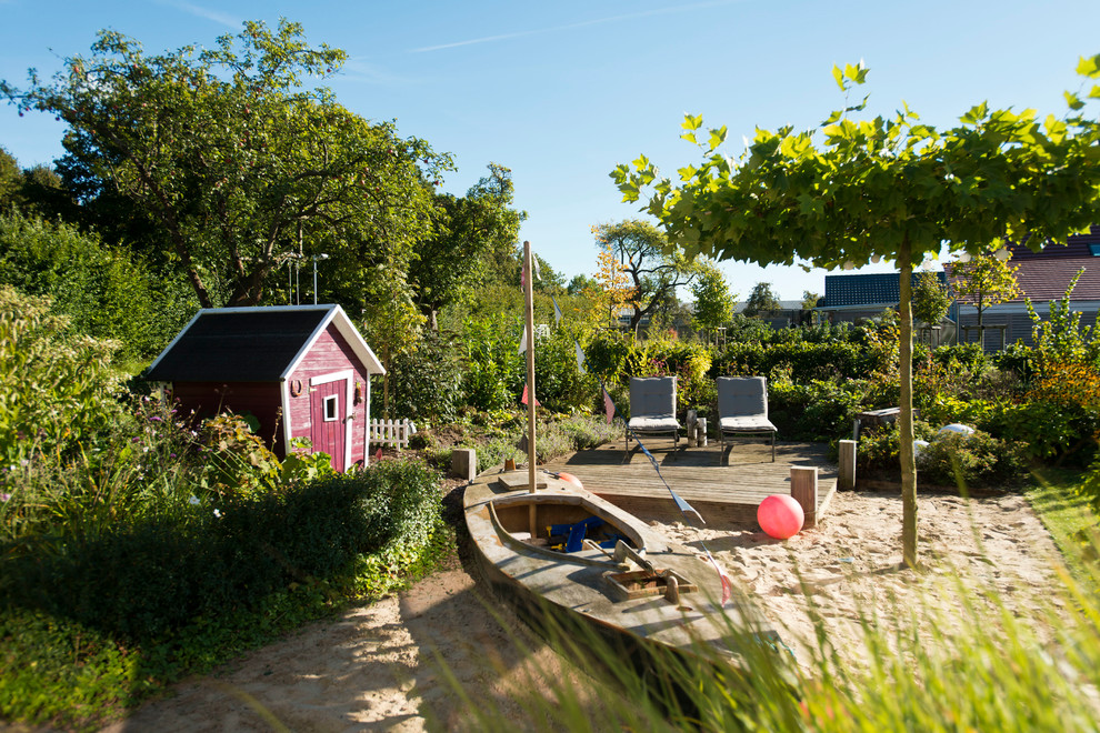 Ejemplo de jardín escandinavo en verano con parque infantil, exposición total al sol y entablado