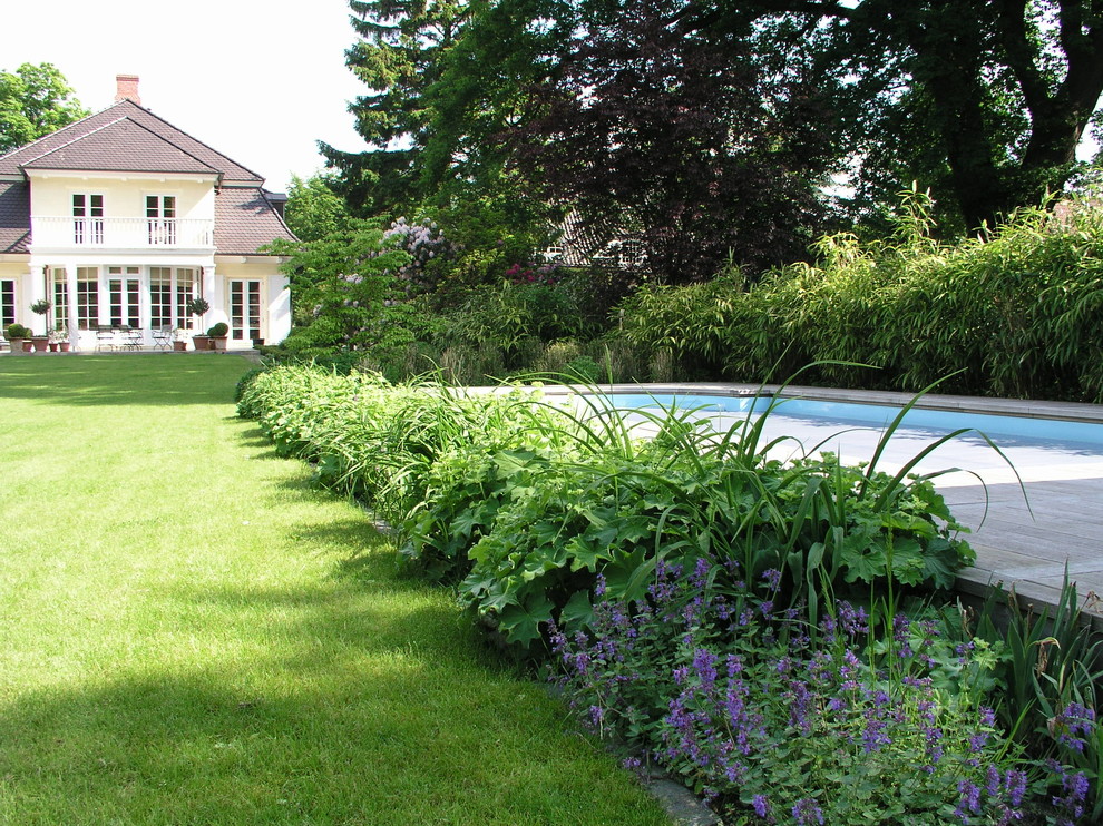 Ejemplo de jardín clásico extra grande en patio trasero con exposición parcial al sol y entablado
