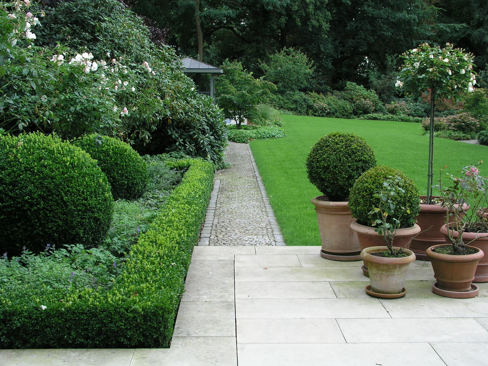 Exemple d'un grand aménagement d'entrée ou allée de jardin arrière chic avec une exposition partiellement ombragée et des pavés en pierre naturelle.