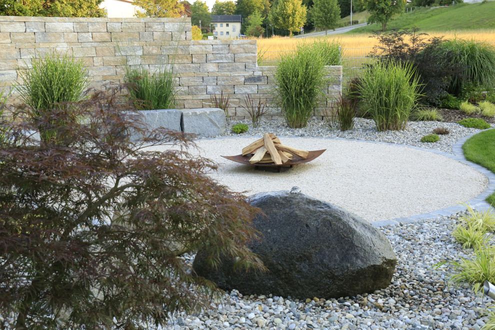 Photo of a large contemporary back full sun garden in Munich with a fire feature and natural stone paving.