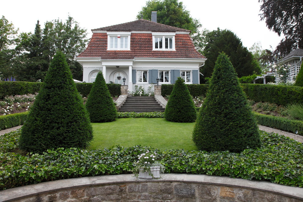 Immagine di un grande giardino formale classico esposto in pieno sole davanti casa con ghiaia e scale