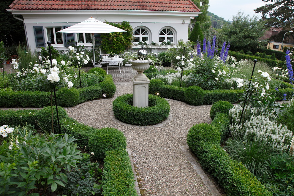 Foto di un grande giardino formale classico esposto in pieno sole dietro casa con un ingresso o sentiero e ghiaia