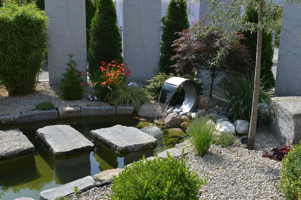 Cette image montre un grand jardin latéral méditerranéen l'été avec un point d'eau, une exposition ensoleillée et du gravier.