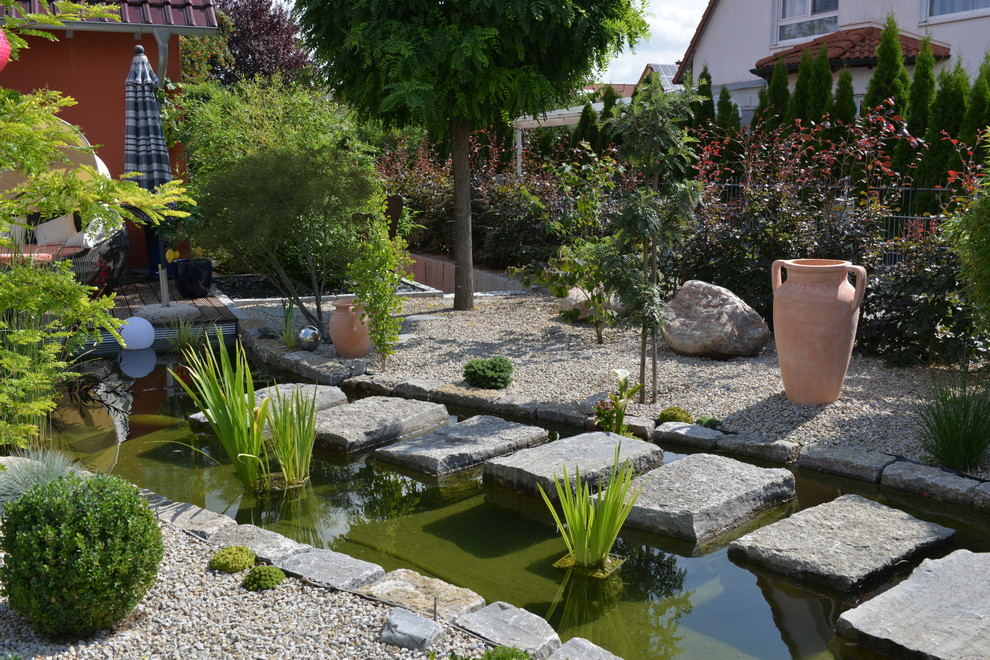 Großer Mediterraner Kiesgarten im Sommer, neben dem Haus mit Wasserspiel und direkter Sonneneinstrahlung in Nürnberg