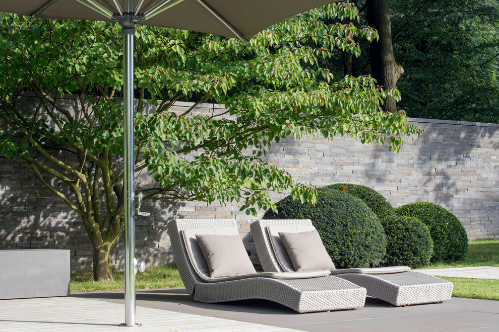 Moderne Gartenmauer im Sommer mit direkter Sonneneinstrahlung und Natursteinplatten in Köln