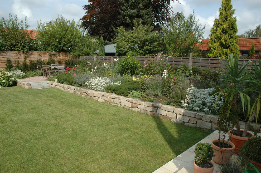 На фото: солнечный участок и сад среднего размера на заднем дворе в современном стиле с подпорной стенкой, хорошей освещенностью и покрытием из каменной брусчатки