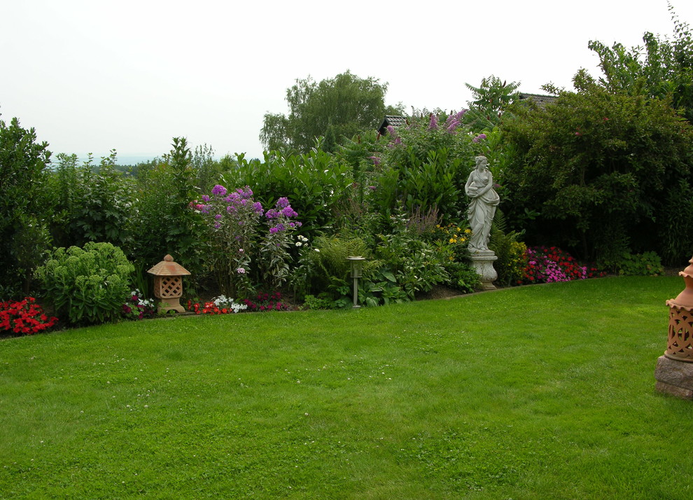 Diseño de jardín mediterráneo grande en verano en patio trasero con exposición total al sol, jardín francés, estanque y adoquines de piedra natural