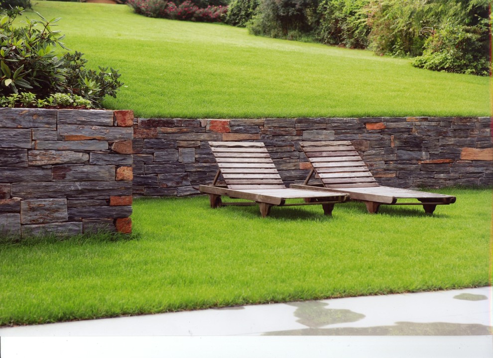 Стильный дизайн: огромный участок и сад на боковом дворе в современном стиле с подпорной стенкой - последний тренд
