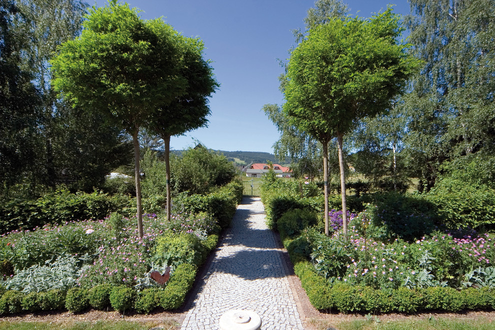 Modelo de camino de jardín clásico grande en verano en patio delantero con jardín francés, exposición parcial al sol y adoquines de piedra natural