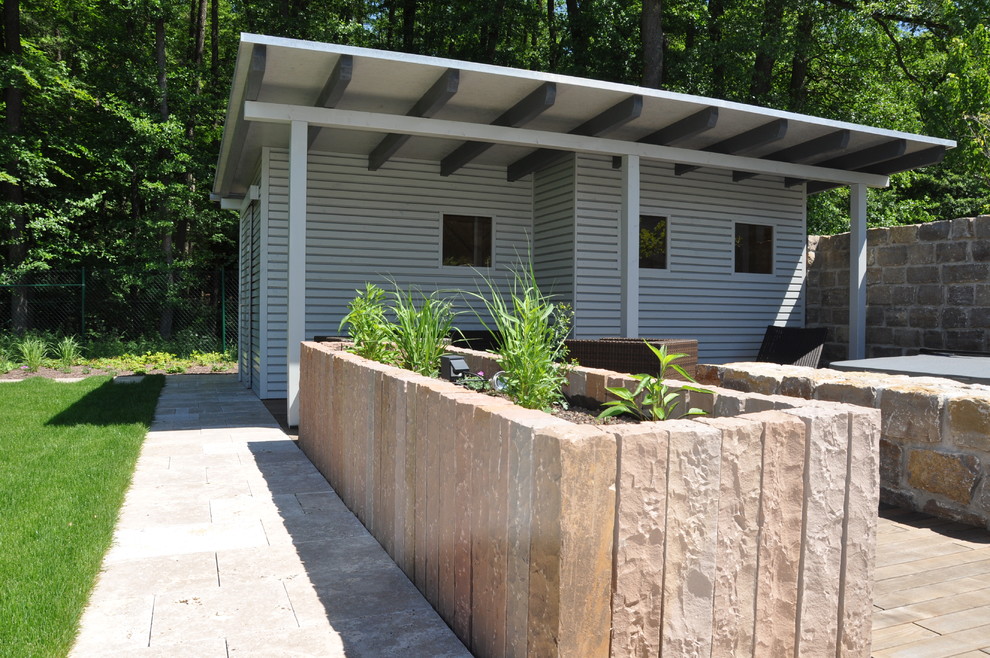 Cette image montre un jardin latéral design de taille moyenne et l'été avec un mur de soutènement, une exposition partiellement ombragée et des pavés en pierre naturelle.