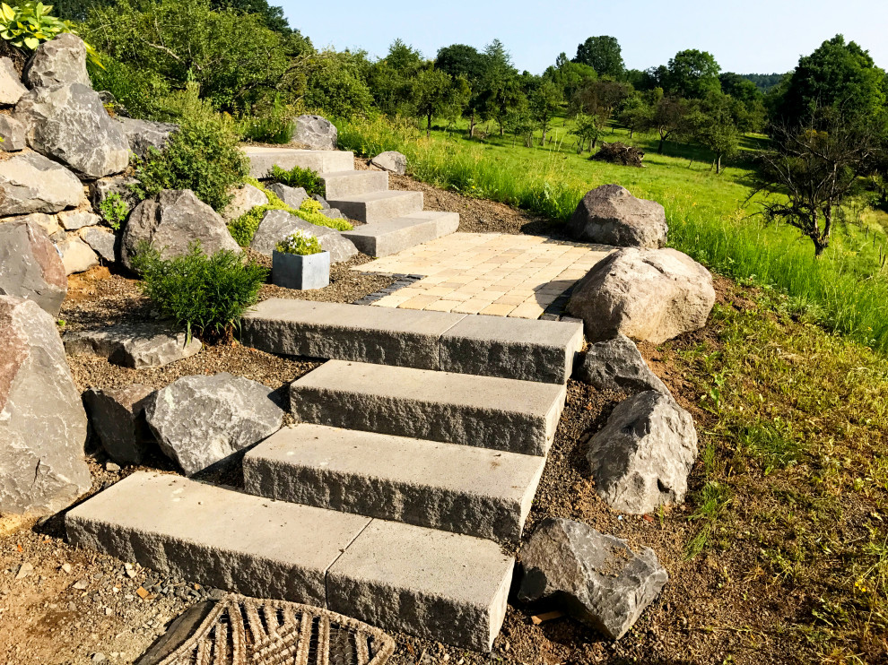 Ispirazione per un giardino contemporaneo con un muro di contenimento e pavimentazioni in pietra naturale