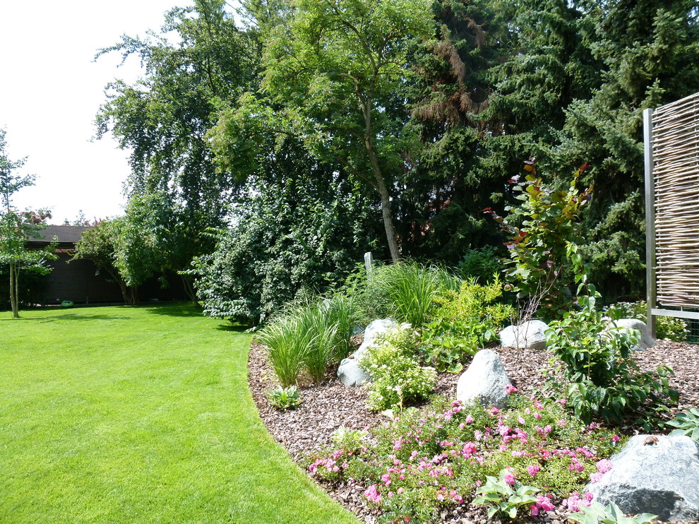 Photo of a mid-sized contemporary full sun and privacy side yard mulch landscaping in Leipzig for summer.