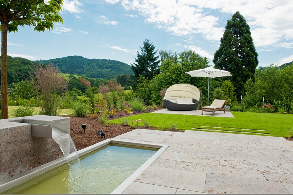 Ejemplo de jardín tradicional de tamaño medio en verano en patio trasero con fuente, exposición total al sol y adoquines de piedra natural