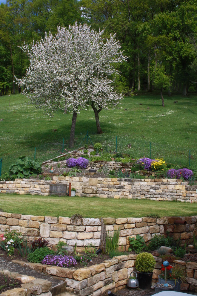 Esempio di un grande giardino chic esposto in pieno sole in primavera con un muro di contenimento e un pendio, una collina o una riva