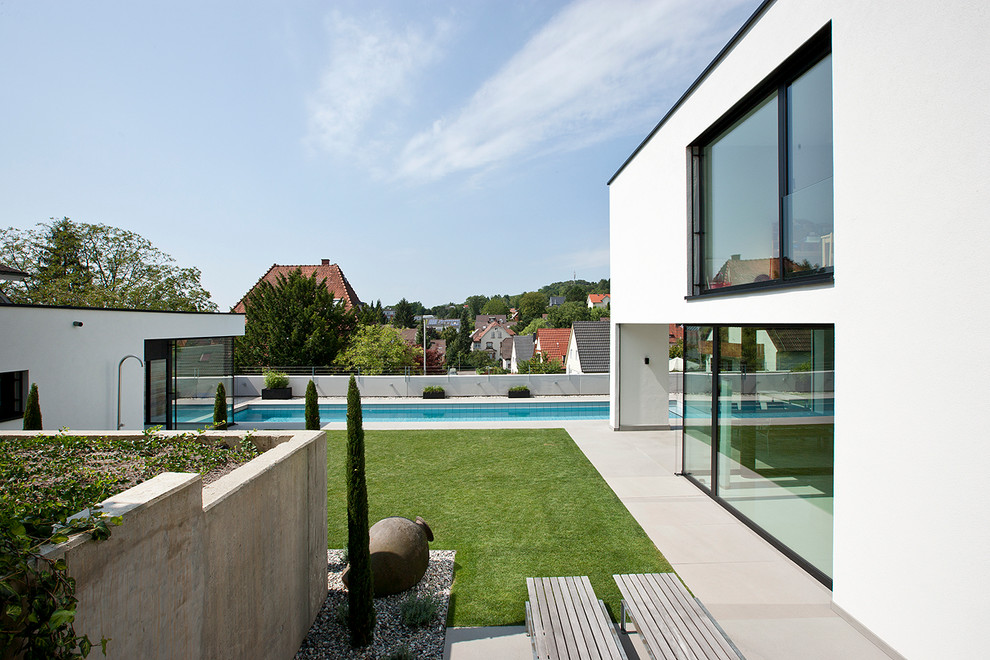 Großer Moderner Garten neben dem Haus, im Sommer mit Wasserspiel, direkter Sonneneinstrahlung und Betonboden in Sonstige