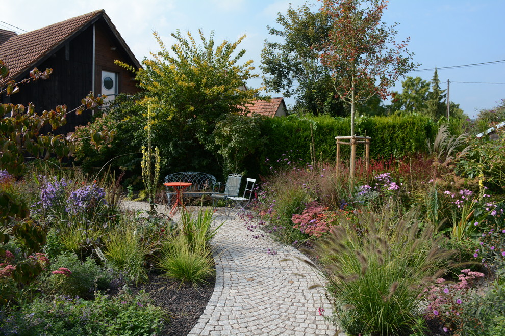 Idéer för att renovera en mellanstor lantlig trädgård i full sol längs med huset på sommaren, med en trädgårdsgång och naturstensplattor