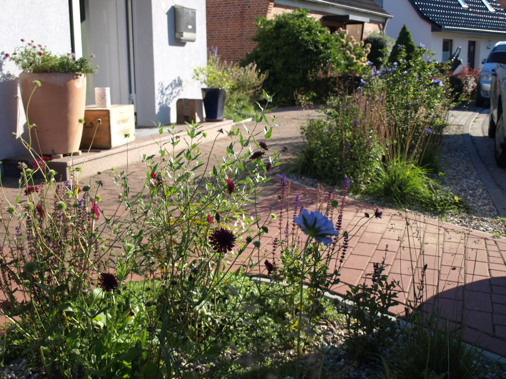 Пример оригинального дизайна: большой летний засухоустойчивый сад на переднем дворе в стиле кантри с клумбами, полуденной тенью и мощением тротуарной плиткой