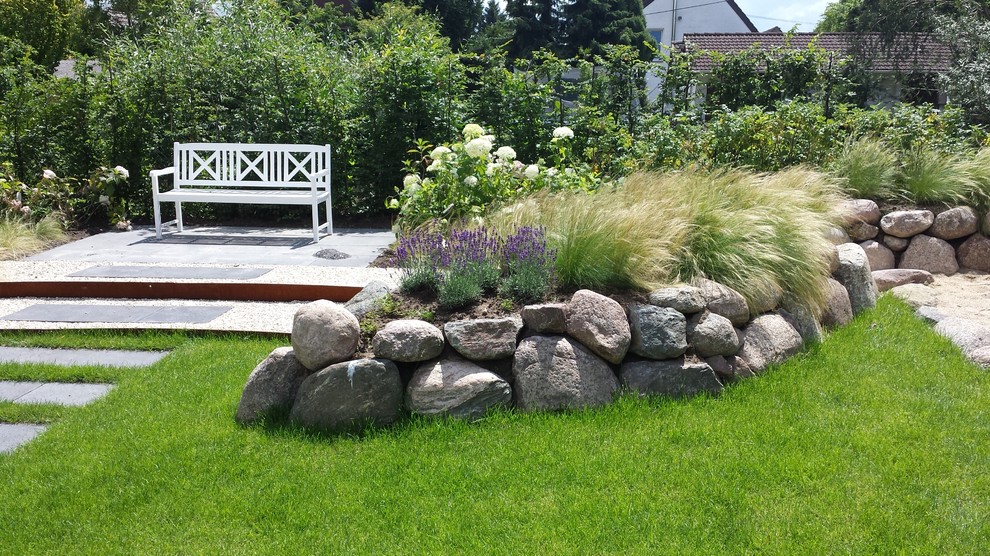 Design ideas for a mid-sized coastal full sun stone retaining wall landscape in Dusseldorf for summer.