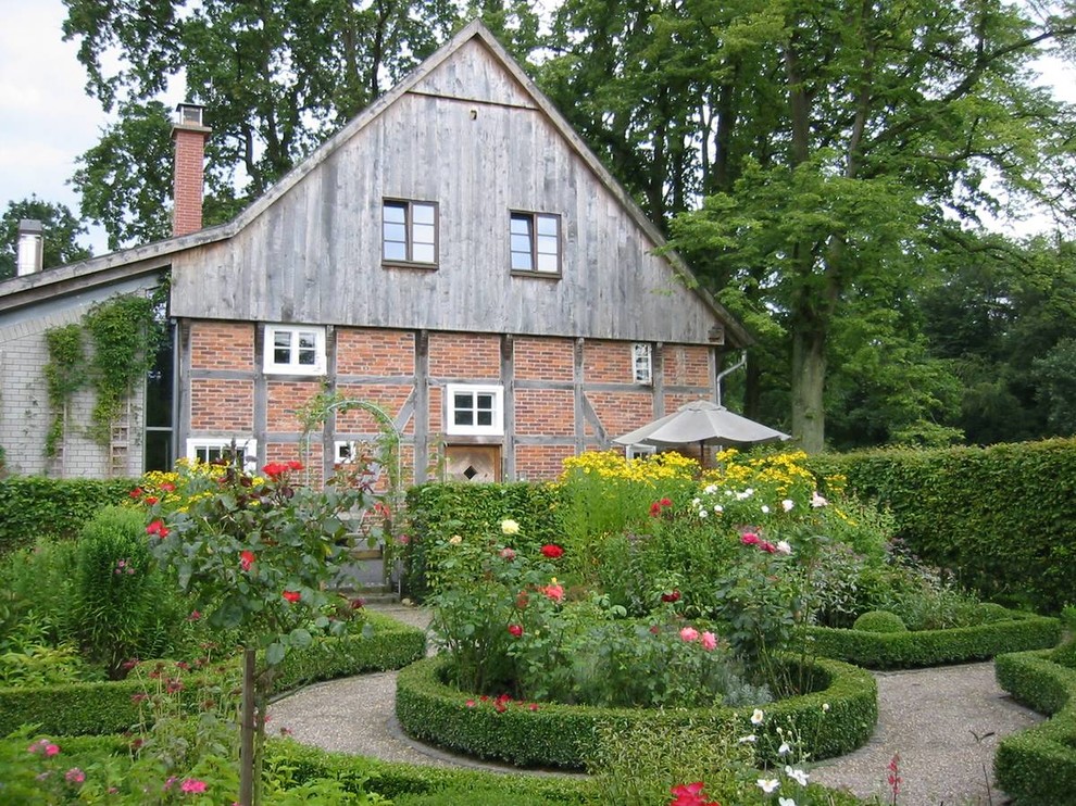 На фото: солнечный, летний регулярный сад среднего размера на заднем дворе в классическом стиле с садовой дорожкой или калиткой, хорошей освещенностью и покрытием из гравия с