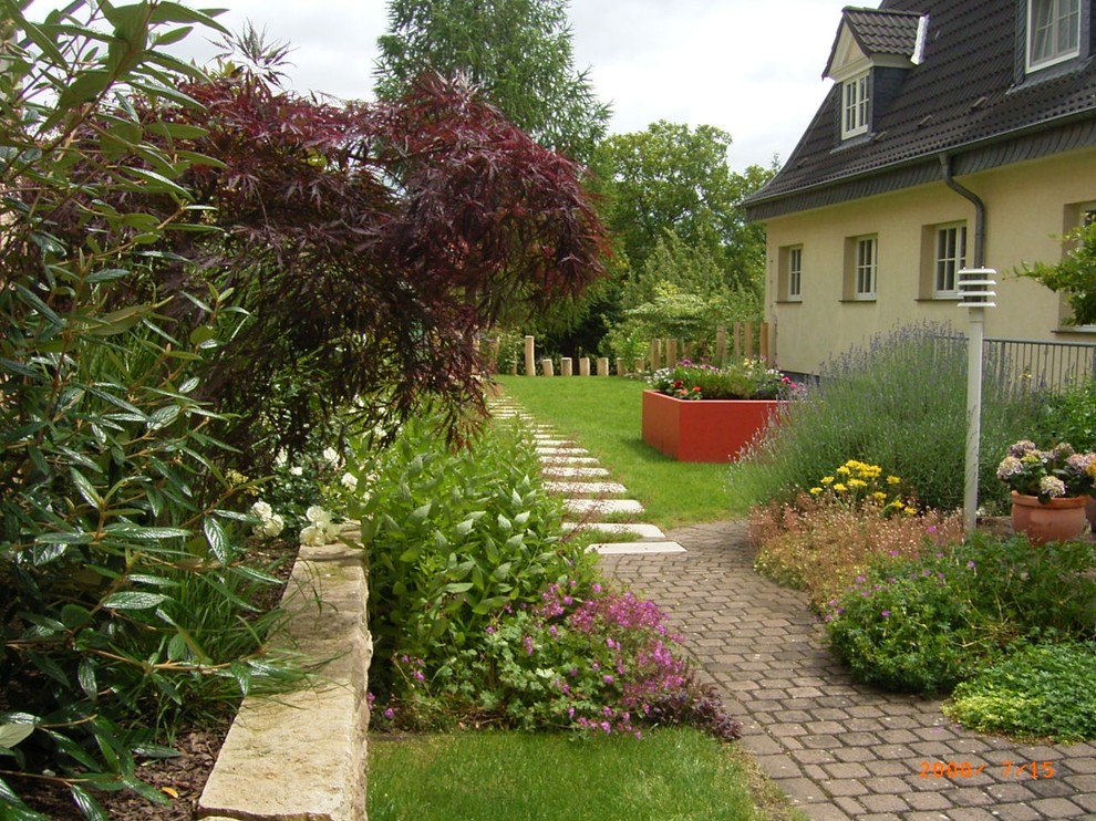 This is an example of a medium sized side full sun garden for summer in Other with a raised bed and natural stone paving.