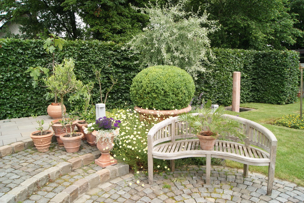 Mediterraner Garten im Sommer mit Kübelpflanzen, Pflastersteinen und direkter Sonneneinstrahlung in Bremen