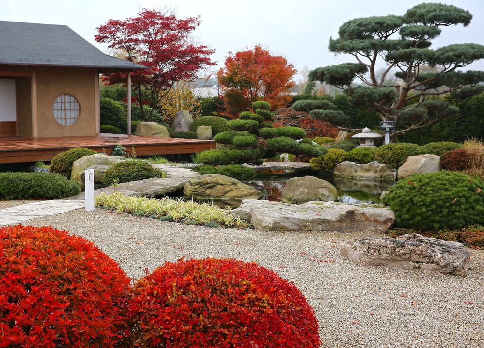 Immagine di un ampio giardino formale etnico esposto in pieno sole dietro casa in autunno con un ingresso o sentiero e ghiaia