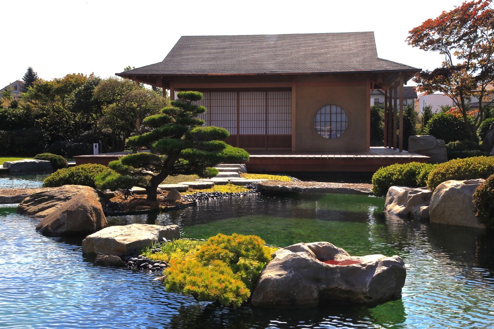 Idéer för en mycket stor asiatisk trädgård i full sol på sommaren, med en fontän och naturstensplattor