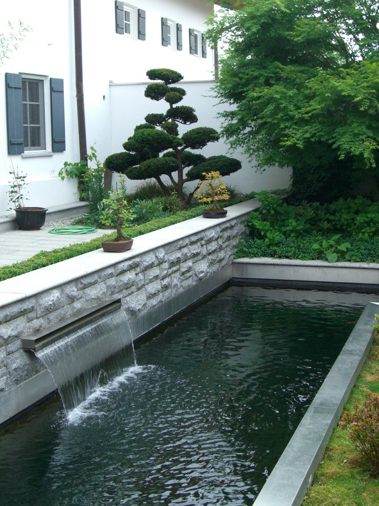 На фото: садовый фонтан среднего размера на заднем дворе в восточном стиле с