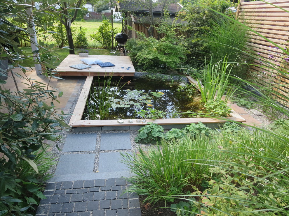 Inspiration för små moderna trädgårdar i delvis sol på sommaren, med en damm och naturstensplattor