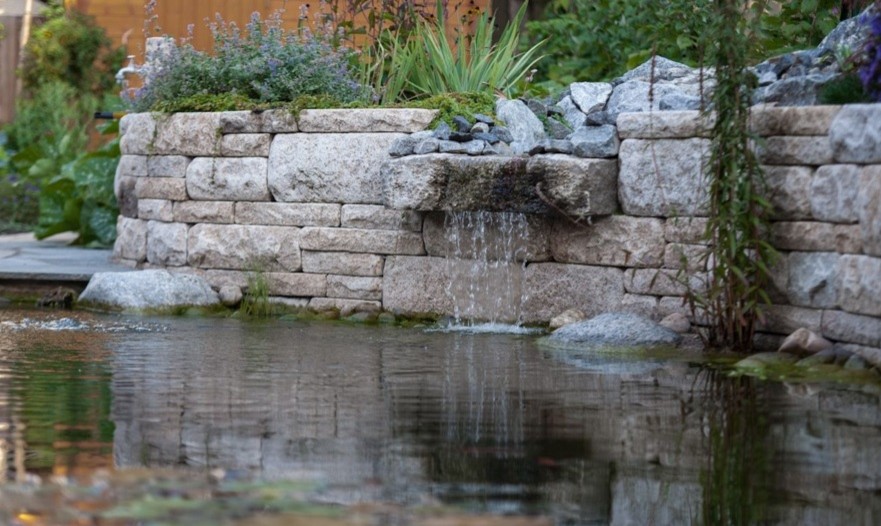 Réalisation d'un jardin latéral champêtre de taille moyenne et l'été avec un bassin, une exposition ensoleillée et des pavés en pierre naturelle.