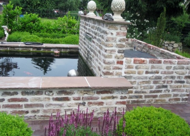 Immagine di un giardino etnico esposto in pieno sole con un muro di contenimento e pavimentazioni in pietra naturale