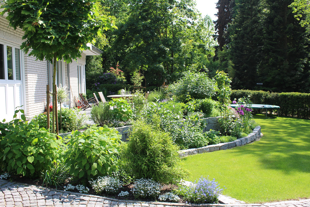 Пример оригинального дизайна: большой летний, солнечный участок и сад в стиле кантри с покрытием из каменной брусчатки, подпорной стенкой и хорошей освещенностью