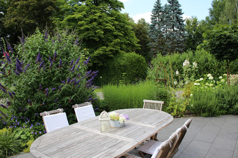 Foto di un grande giardino classico esposto in pieno sole in estate con pavimentazioni in pietra naturale