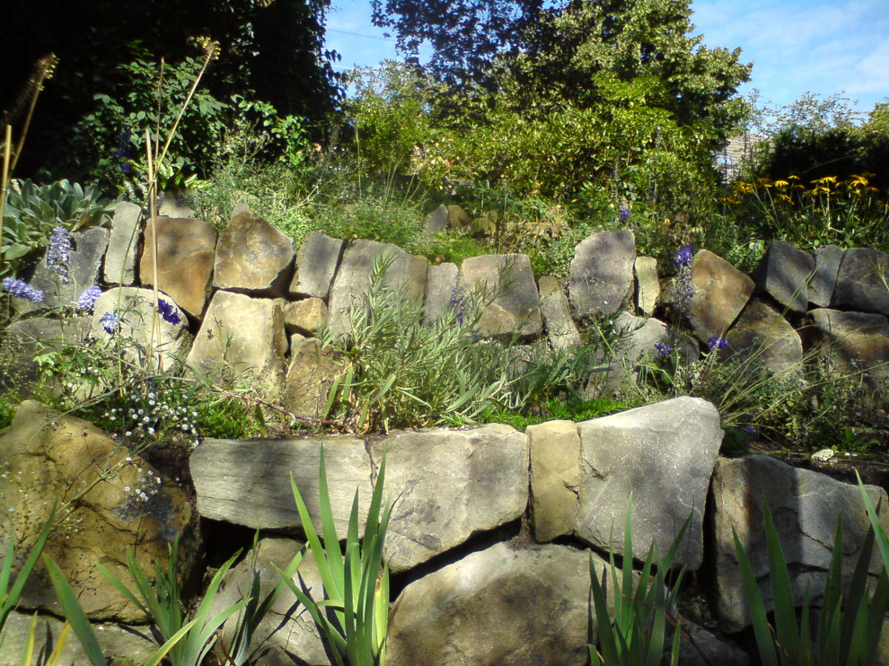 Ejemplo de jardín campestre extra grande con muro de contención