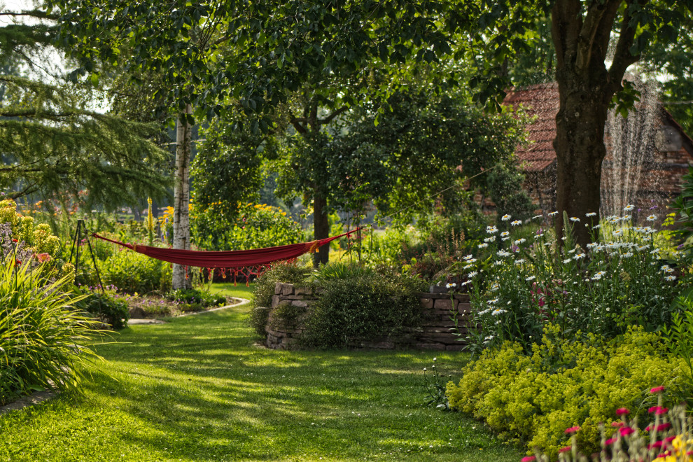 Esempio di un grande giardino country esposto a mezz'ombra dietro casa in estate con un muro di contenimento e pavimentazioni in pietra naturale