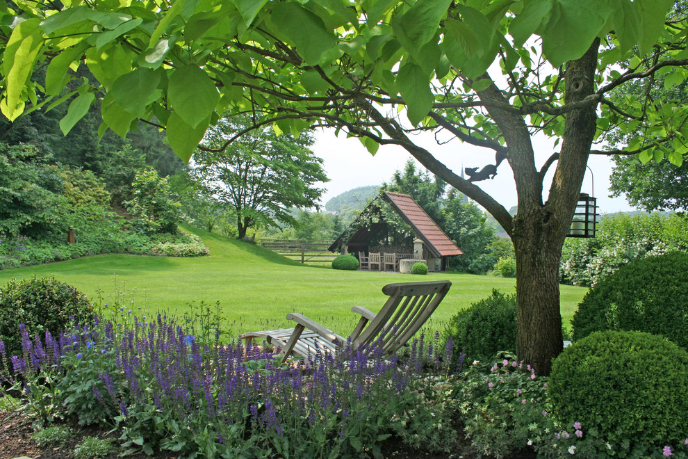 Imagen de jardín clásico extra grande en verano en ladera con exposición parcial al sol