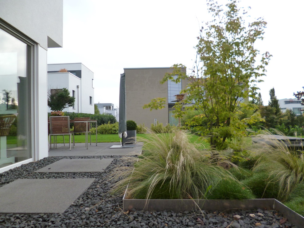 Réalisation d'un petit jardin latéral minimaliste l'été avec une exposition ensoleillée et du gravier.